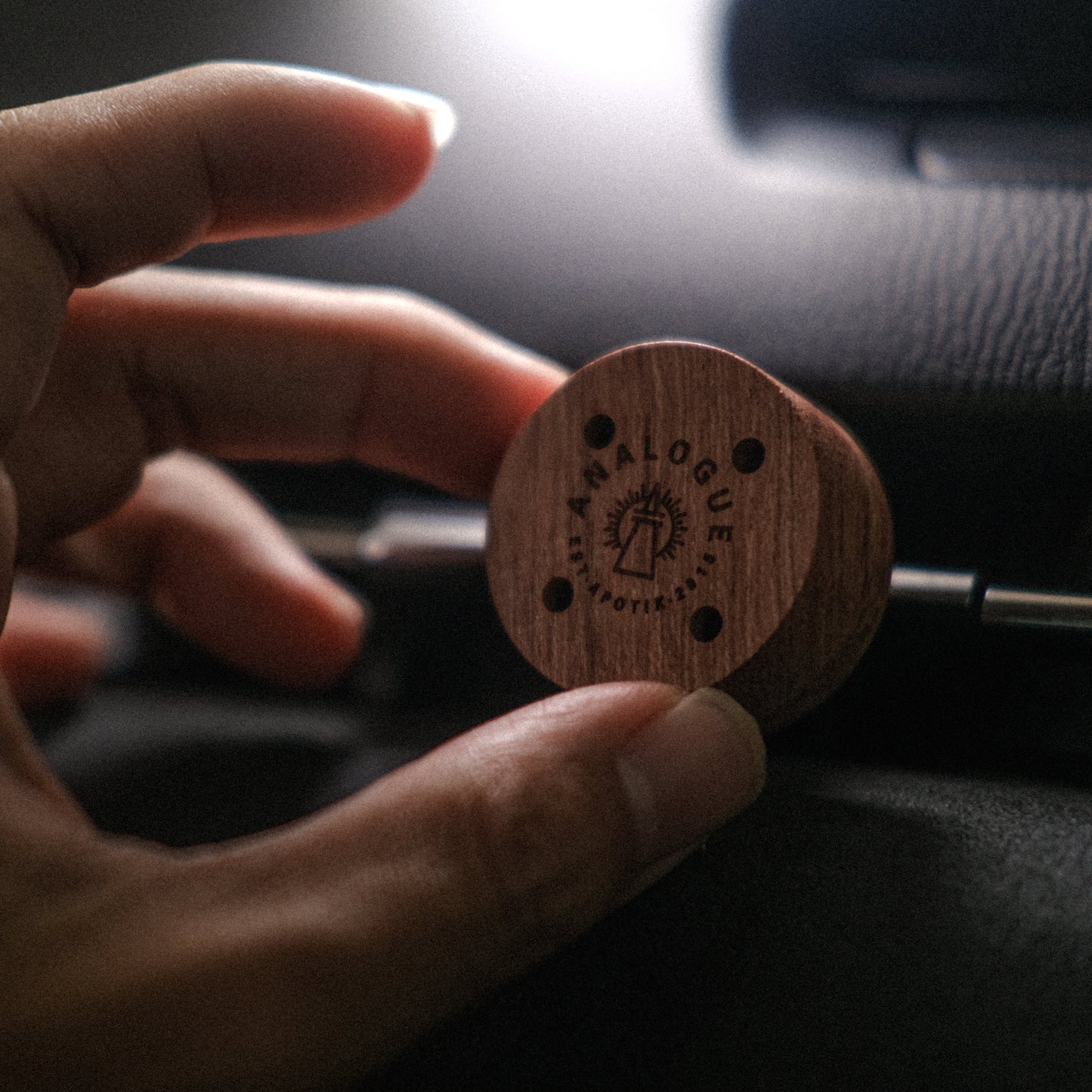 Hand holding a wooden product with 'Black Balcony' branding against a dark background