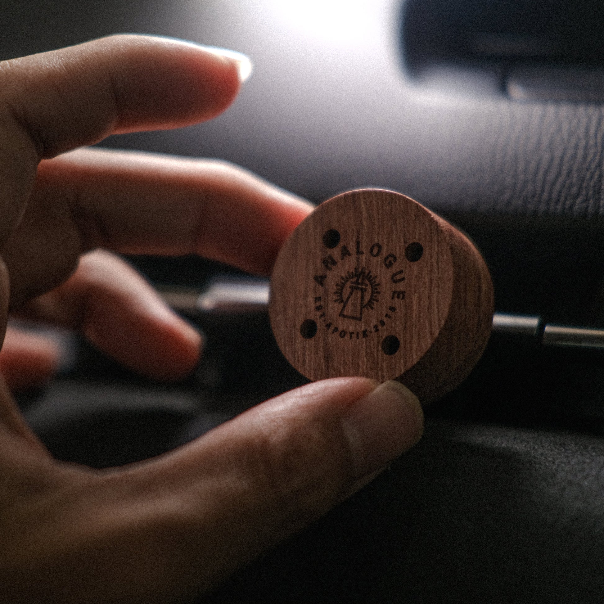 Hand holding a wooden product with 'Black Balcony' branding against a dark background